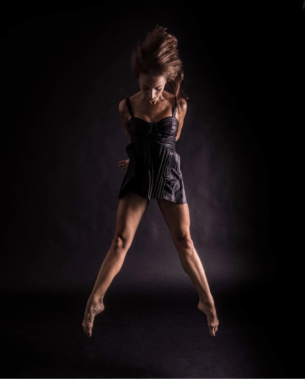 Buse Babadag in black dress, hair flying mid-leap